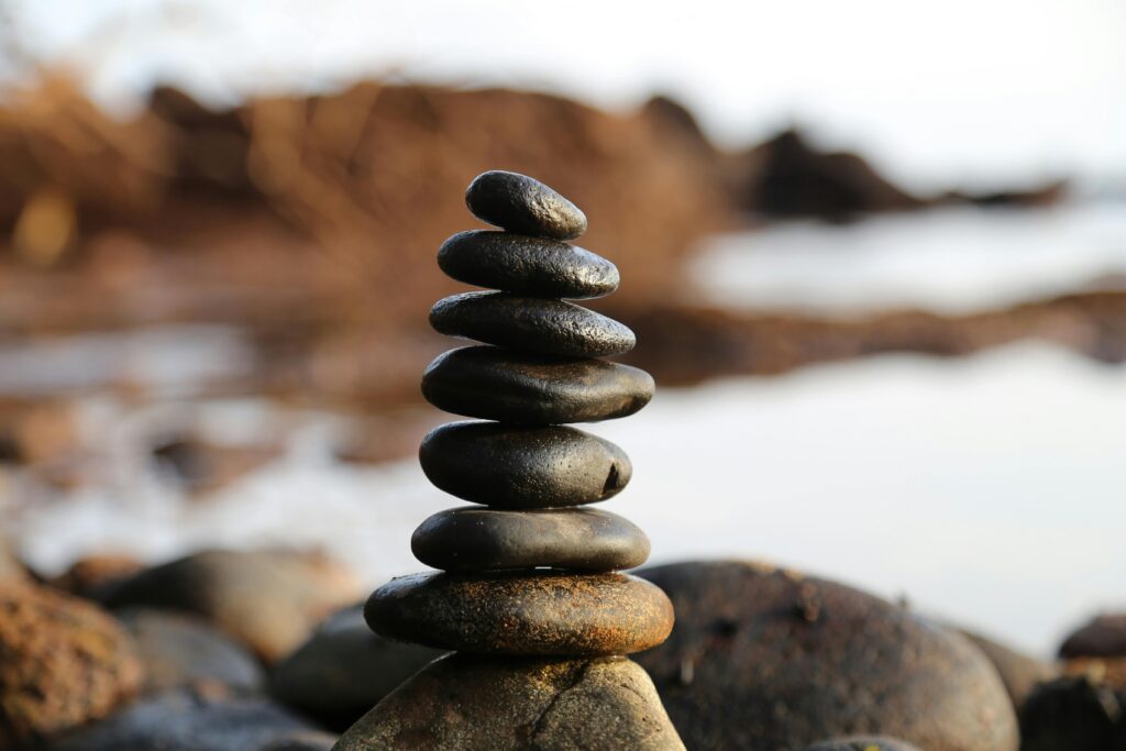 Eneseareng vol 1 A stack of smooth stones artfully balanced by a waterside, evoking tranquility and zen.
