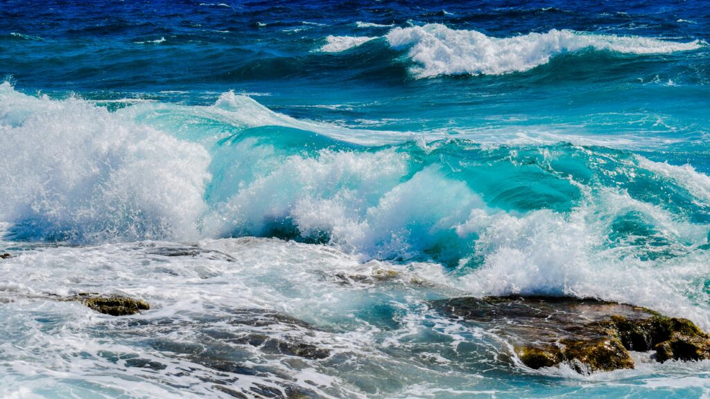 pexels photo 414320 414320 Vibrant blue ocean waves crashing against rocky shoreline under clear summer skies.